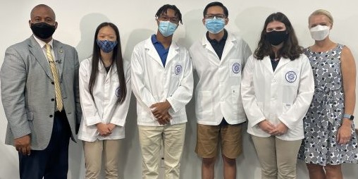  Superintendent House stands with students dressed in white lab coats at DeBakey High School