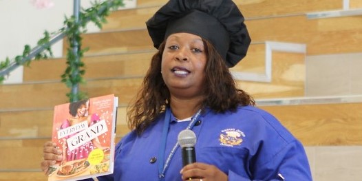  Jocelyn Delk Adams speaks to students, holding her cookbook