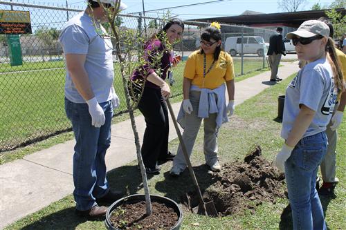 Mrs. Parra smiling as she finishes digging a hole for her tree.